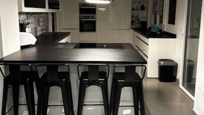Een moderne keuken met een centraal eiland, barkrukken en inbouwapparatuur.