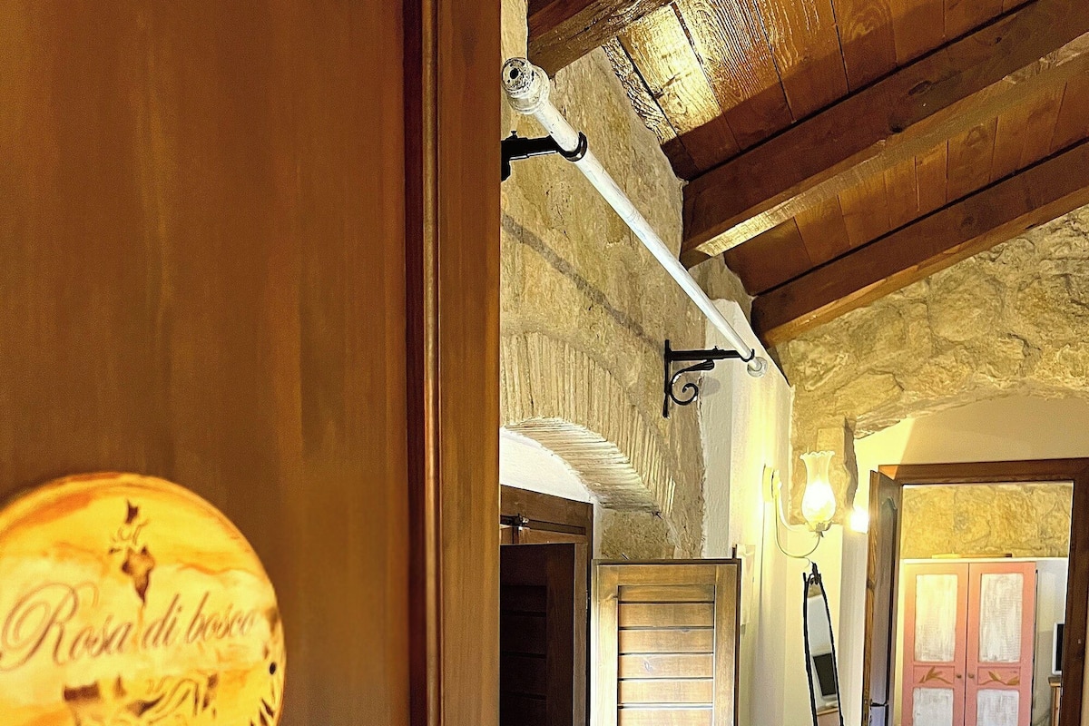 Un interior de madera con un letrero que dice 'Rosa di bosco', un banco de madera y un piso de baldosas.