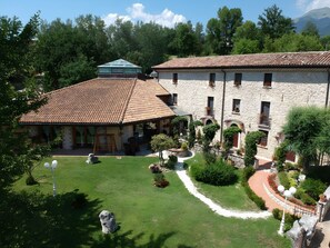 Un patio con edificios de piedra, un pequeño jardín y cielo despejado.