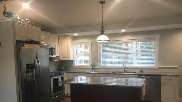 A modern kitchen with a central island, stainless steel appliances, and a pendant light. - 01) Hidden Treasures of Treasure Island NPR (New Port Richey)