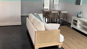 Ein gemütliches Wohnzimmer mit einer Couch, einem Esstisch und einem Bild von Booten an der Wand.