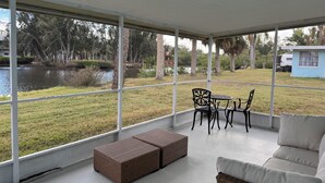 Ein überdachter Außenbereich mit Tisch, Stühlen, Korpusstützmöbeln und einer Couch.