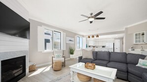 A modern living room with a fireplace, grey sofa, white coffee table, and a ceiling fan.