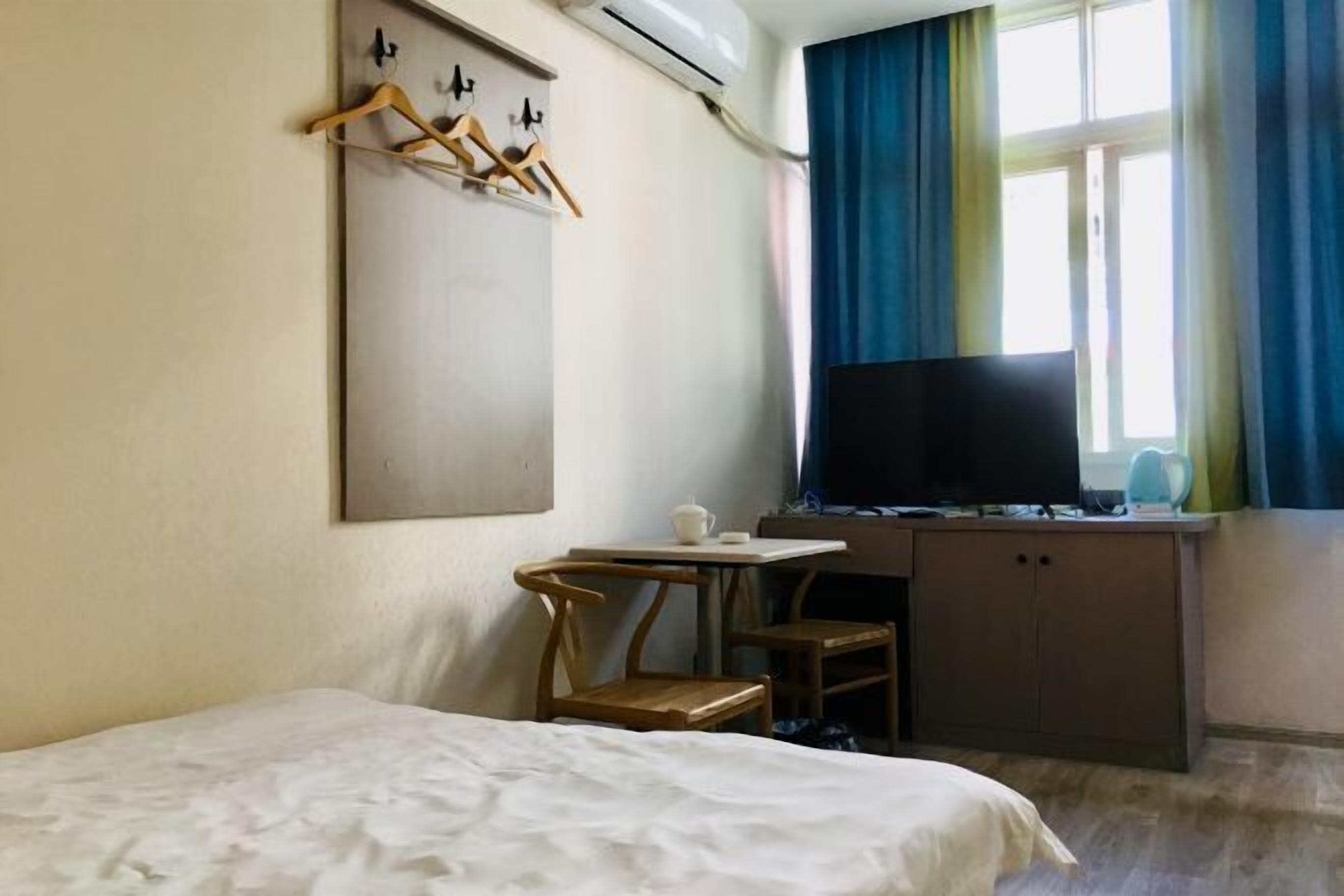 Une chambre d’hôtel comprenant un lit, un bureau avec une télévision, une chaise et une armoire.