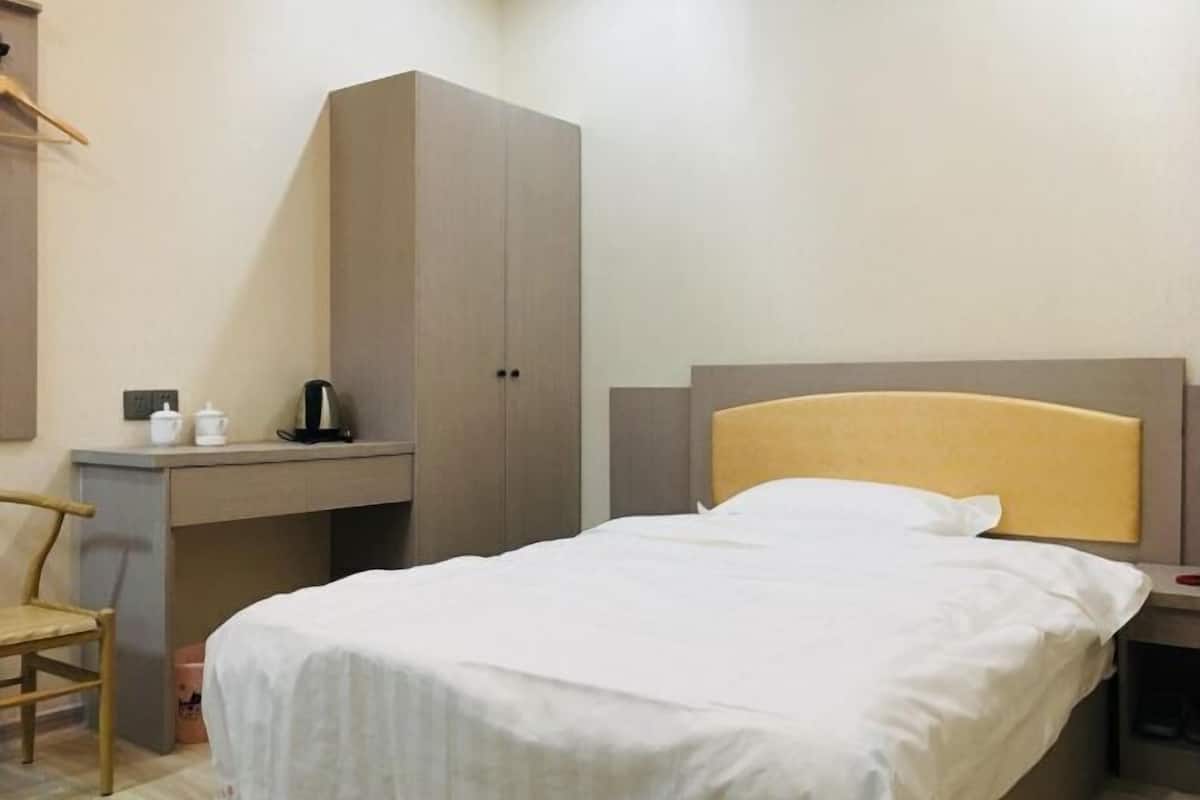 Una cama individual con cabecera, un escritorio con silla y un armario.
