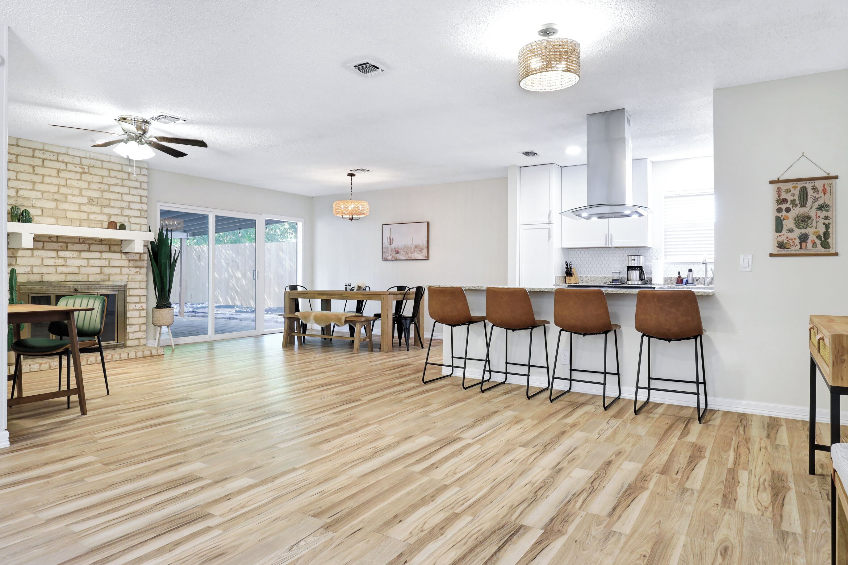 A spacious kitchen with a brick wall, wooden flooring, and a dining area with bar stools.