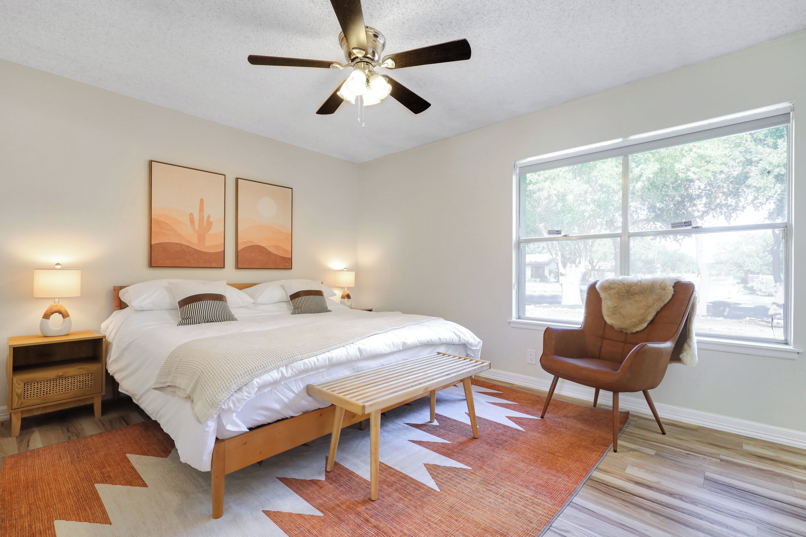 Ein Schlafzimmer mit Bett, Stuhl, Deckenventilator und Fenster.