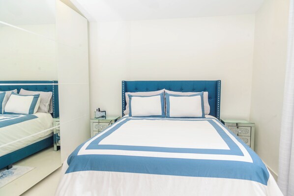 Een slaapkamer met een bed, twee nachtkastjes en een spiegel.
