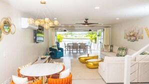 Una sala de estar moderna con comedor, un conjunto de sofás y una escalera.