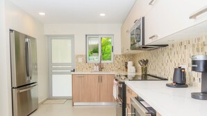 Una cocina moderna con electrodomésticos de acero inoxidable, una isla de madera y vistas a través de una ventana.