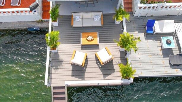 Una terraza en la azotea con mobiliario exterior, piscina y vistas al agua.