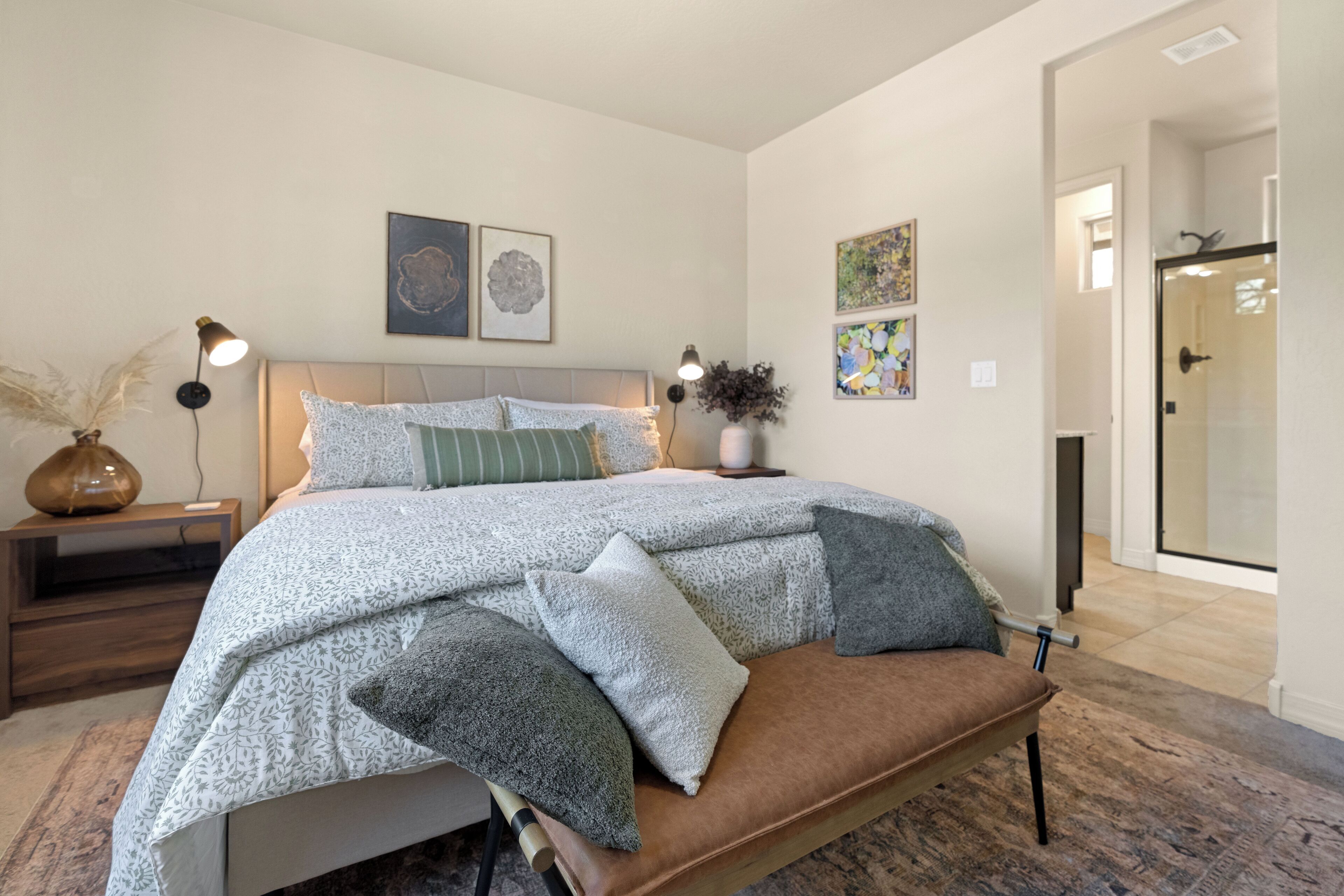 Quarto com cama, mesas de cabeceira e um banco.