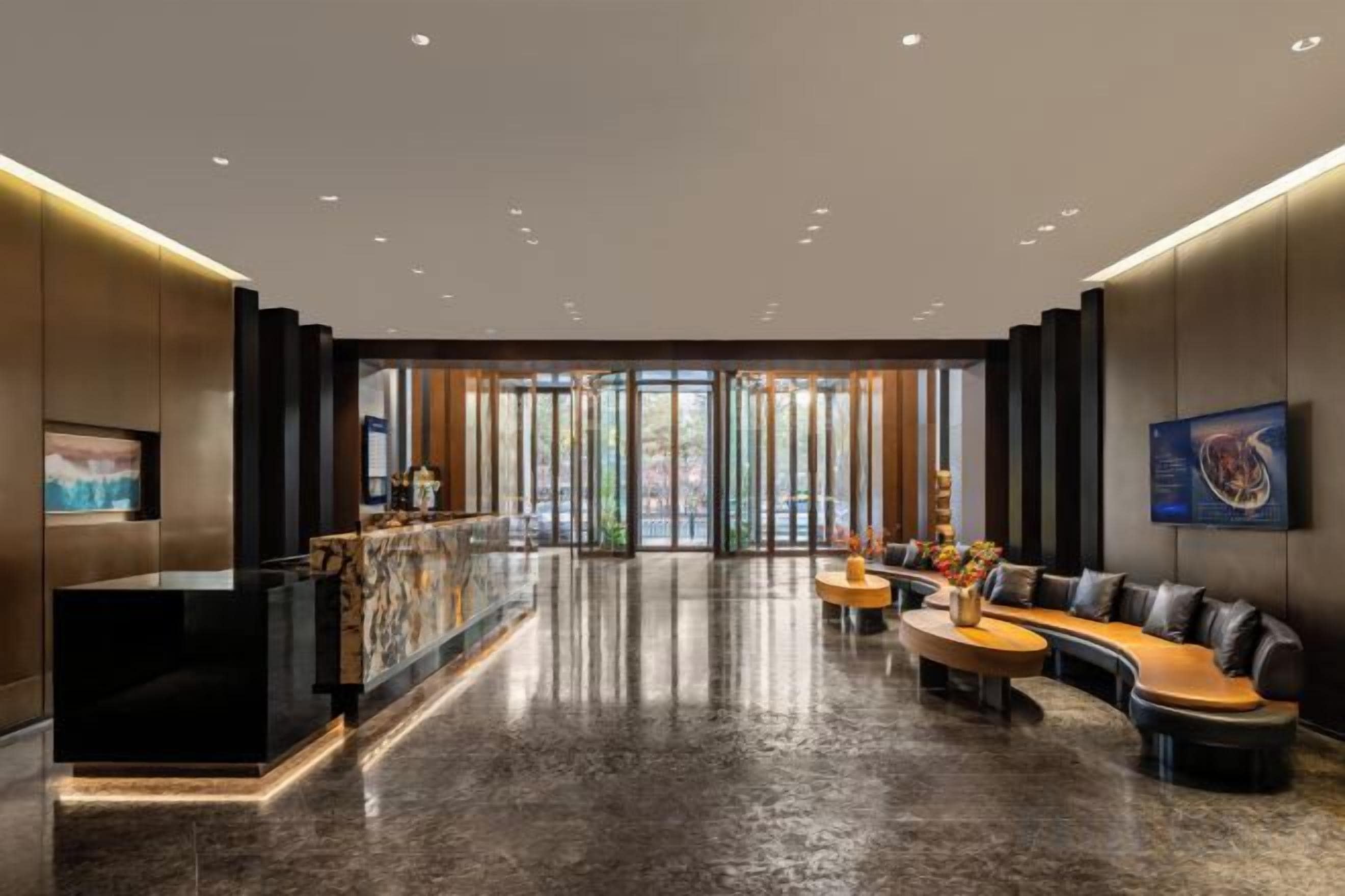 A modern lobby with a reception desk, seating area, and large windows.
