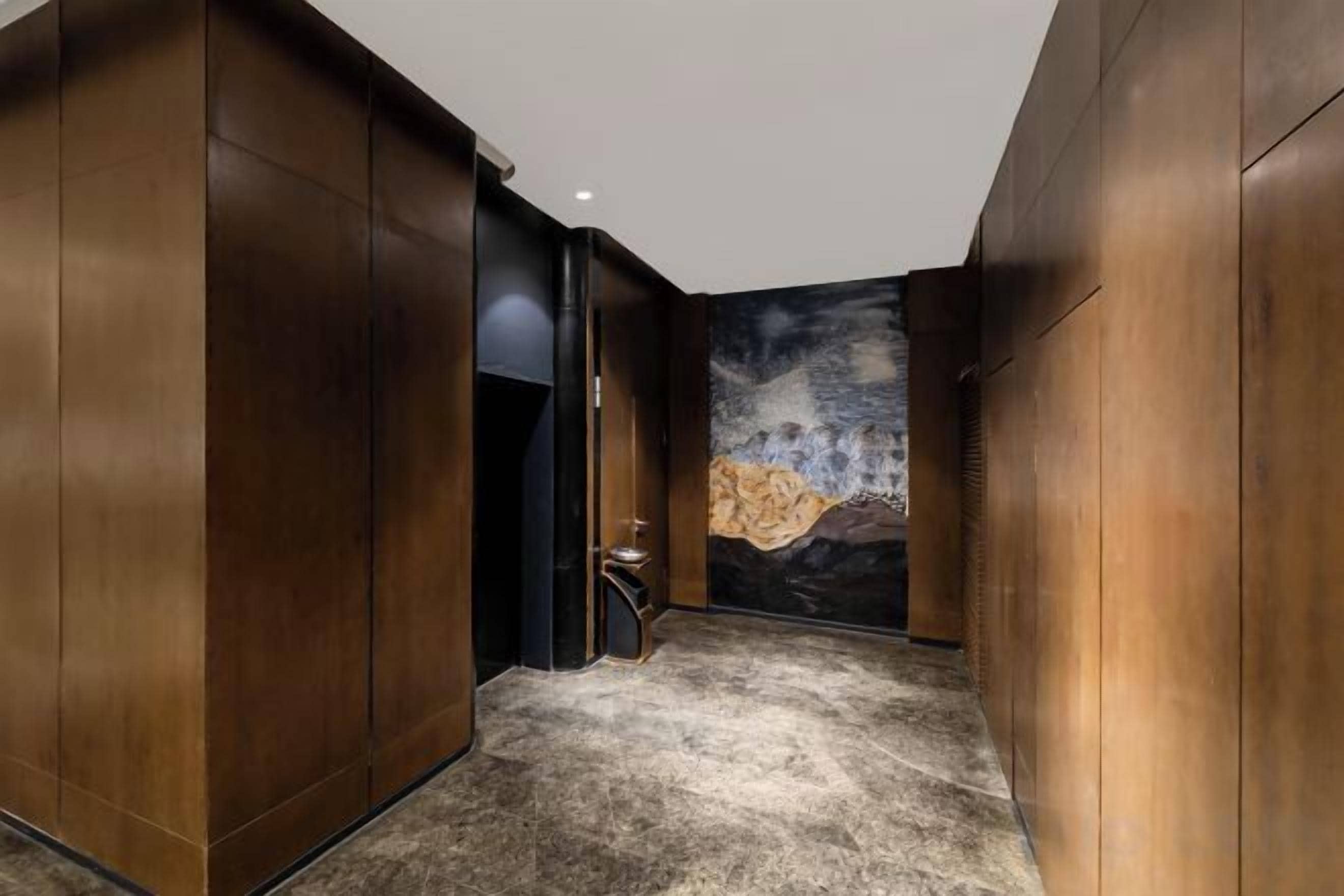 A hallway with wooden paneling and a textured floor.