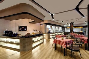 A restaurant with a counter, tables with red and white checkered tablecloths, and a brick wall.