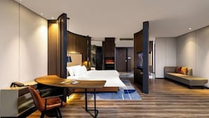 A modern hotel room with a bed, a desk, a sofa, and a fireplace. - Fengdu Hotel (Harbin) (Harbin)