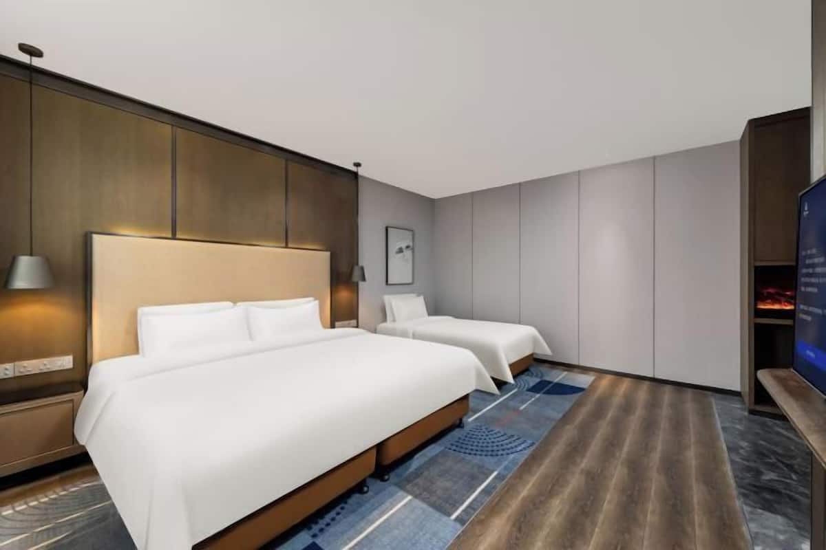 A hotel room with two beds, a large TV, and a modern design.