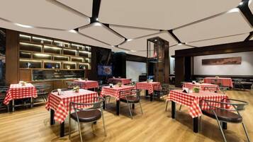 A restaurant with multiple tables covered in red and white checkered tablecloths, wooden flooring, and a modern ceiling design.
