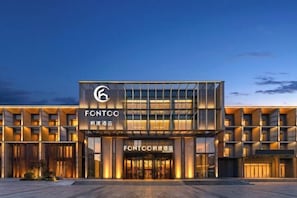 Um hotel moderno com um logotipo em destaque, fachada de vidro e entrada bem iluminada.