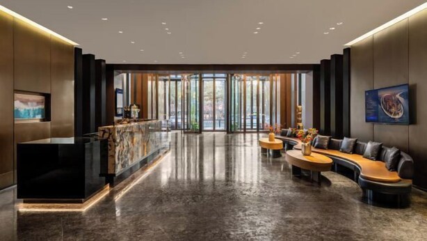 A modern lobby with a reception desk, seating area, and large windows. - Fengdu Hotel (Harbin) (Harbin)