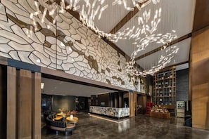 A modern lobby with a unique geometric wall design, a reception desk, and seating area. - Fengdu Hotel (Harbin) (Harbin)