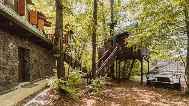A rustic cabin with a stone exterior, wooden deck, and a treehouse with a staircase. - Accogliente chalet sul vulcano Etna, In Sicilia. Situato a quota 1500. (Nicolosi)