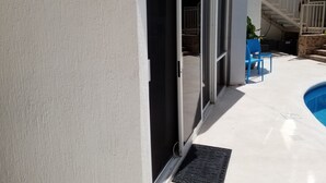 A poolside area with a sliding glass door leading to a covered patio. - Depa una recamara en la playa (Bucerías)