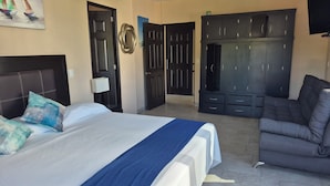Ein Hotelzimmer mit Bett, Sofa, Fernseher und Kleiderschrank.