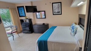 A hotel room with a bed, a desk, a chair, a TV, and a window with curtains. - Estudio frente a la playa (Bucerías)