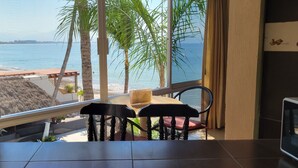 A balcony with a table and chairs overlooking a beach and ocean. - Estudio frente a la playa (Bucerías)