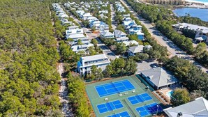 Un quartier résidentiel avec des maisons, un court de tennis et une plage en arrière-plan.