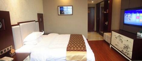 A hotel room with a bed, a television, a desk, and a mirror.