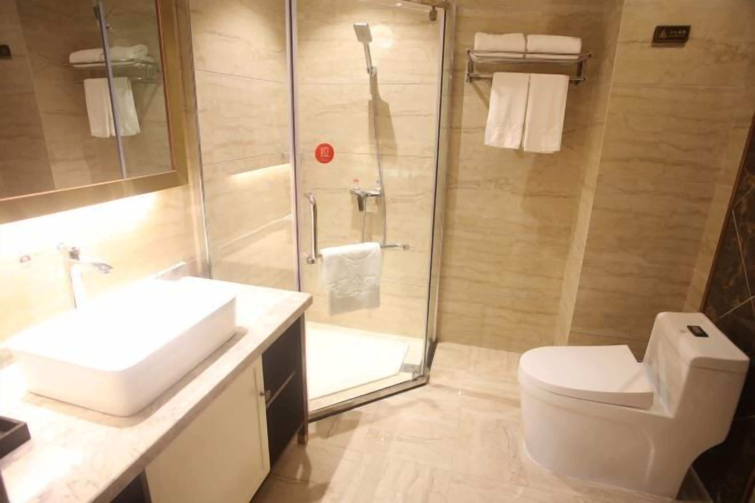 A bathroom with a glass-enclosed shower, a white sink, and a toilet.