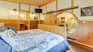 Una stanza in legno con un letto, uno specchio rotondo e un soffitto in legno.