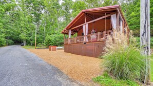 A wooden cabin with a balcony, surrounded by dense forest. - Murray Cabin w/ Hot Tub: Walk to Kentucky Lake! (Murray)