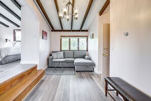 Une pièce comprenant un canapé d’angle, un banc, une petite table et un escalier avec des marches en bois.