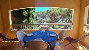 A balcony with a table set for four, overlooking a garden with trees and a clear sky. - Beautiful apartment with pool in Sainte-Maxime (Sainte-Maxime)