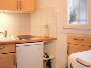 Une cuisine de taille réduite, équipée d’un évier, d’un petit réfrigérateur, d’un plan de travail et d’une fenêtre.