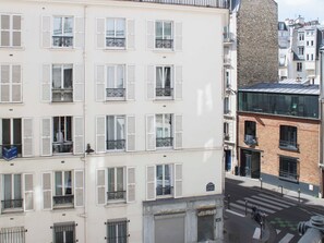 Un immeuble à plusieurs étages, doté de façades blanches, de nombreux balcons et donnant sur la rue.