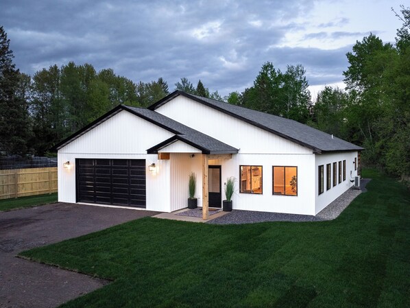 A modern single-story house with a garage, large windows, and a well-maintained lawn. - Walking distance to Pike Lake beach, hot tub & game room, pet friendly (Duluth)