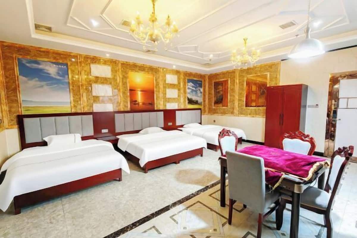 Een hotelkamer met drie bedden, een eettafel met stoelen en een kroonluchter.