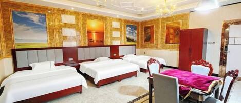 A hotel room with three beds, a dining table with chairs, and a chandelier.