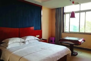 Une chambre d’hôtel avec un lit, un bureau et une fenêtre avec des rideaux.