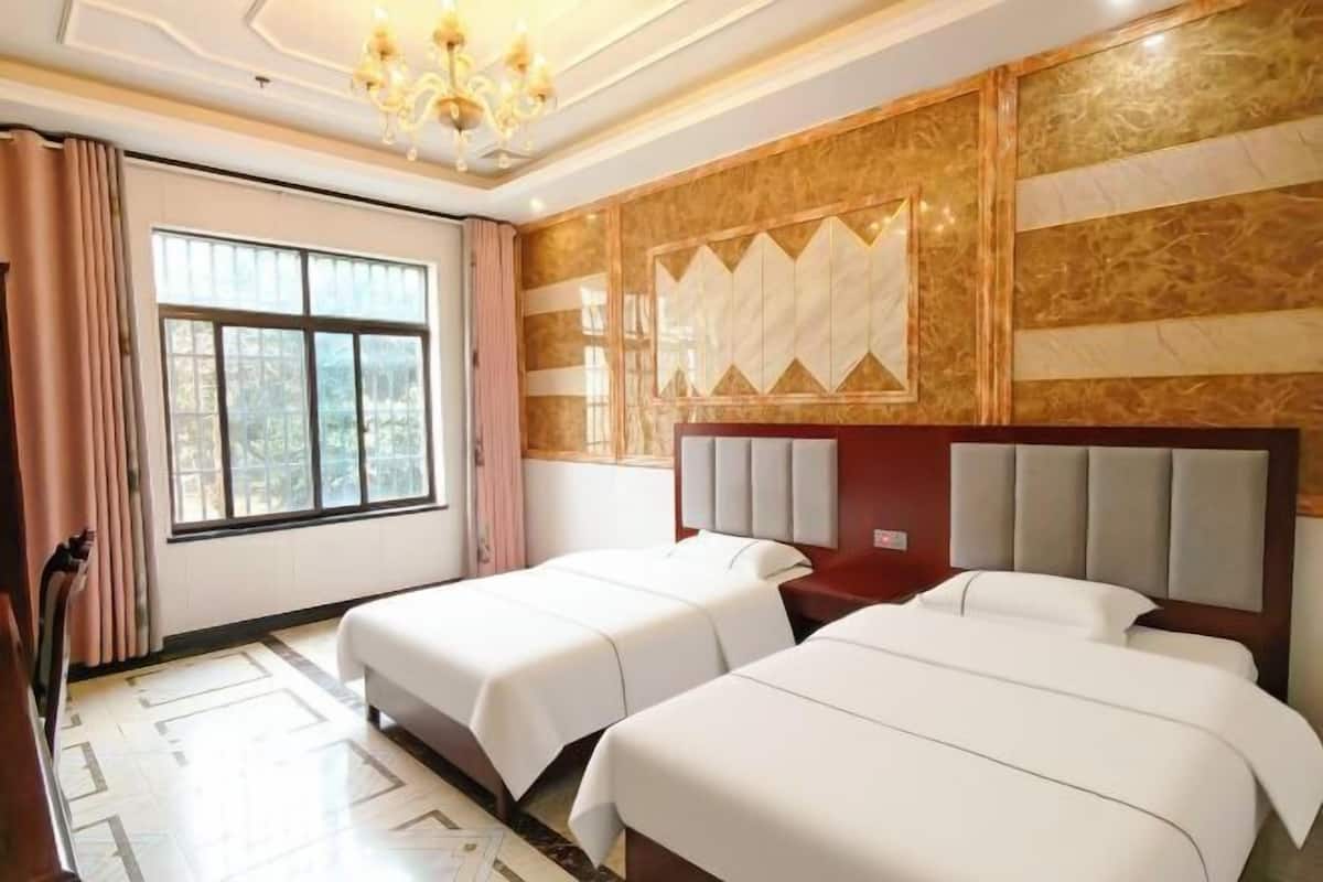 Een hotelkamer met twee bedden, een groot raam, een kroonluchter en een behang met patroon.