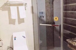 Une salle de bain avec une porte en verre, un porte-serviettes et un miroir.