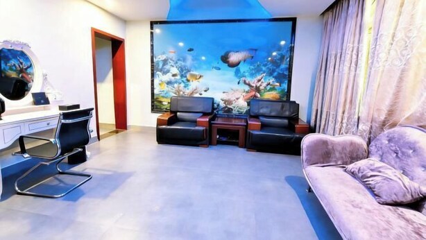 Una sala de estar moderna con un acuario grande, un sofá, una silla y un escritorio.
