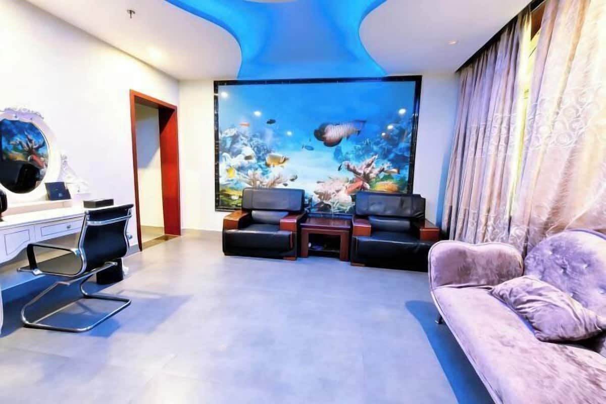 Een moderne woonkamer met een groot aquarium, een bank, een stoel en een bureau.