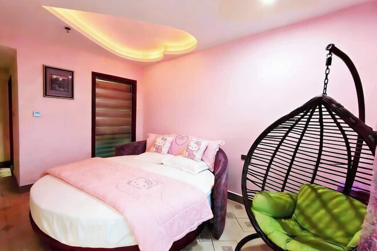 Een slaapkamer met een bed, een hangstoel en een deur.
