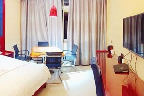 Une chambre d’hôtel comprenant un lit, un bureau avec une chaise, une télévision et des rideaux.