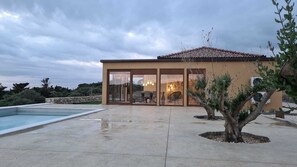 Una casa moderna con piscina, grandes puertas de cristal y un área de patio.